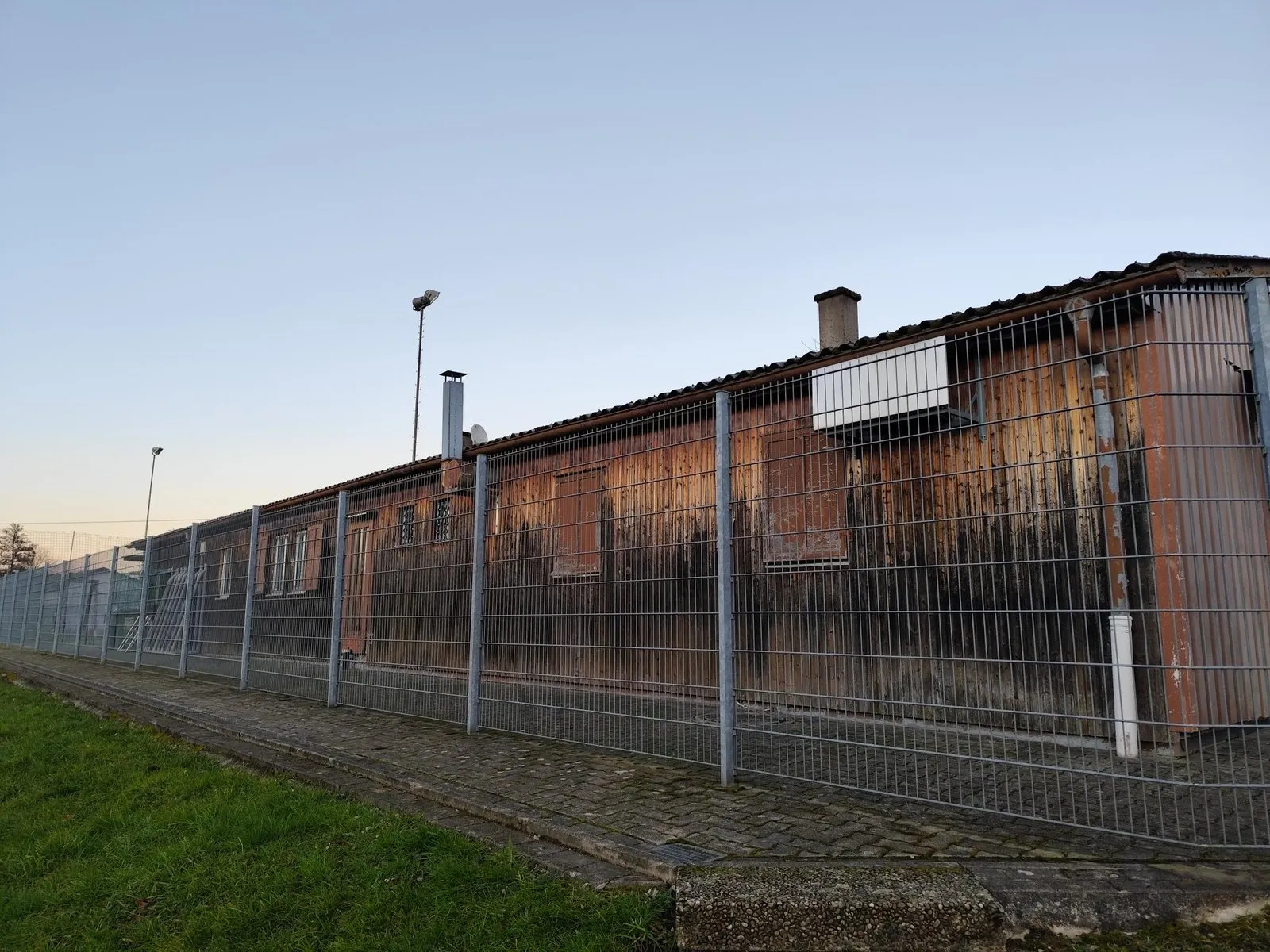 Längsseite des Clubhauses: stark verwitterte und ausgeblichene Holzverschalung über die gesamte Gebäudelänge